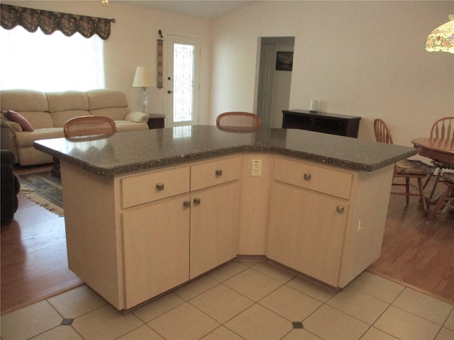 kitchen with a center island, open floor plan, dark stone countertops, and light tile patterned floors