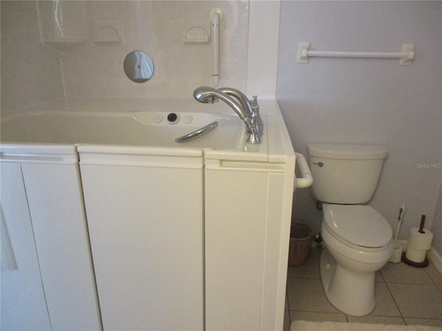bathroom featuring toilet, tile patterned floors, and a tub to relax in