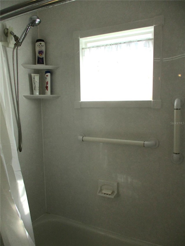 bathroom with shower / tub combo with curtain and a wealth of natural light