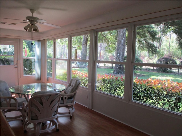sunroom with baseboards, wood finished floors, and a wealth of natural light