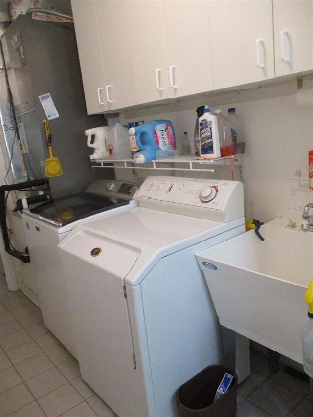 clothes washing area featuring a sink, separate washer and dryer, cabinet space, and light tile patterned flooring