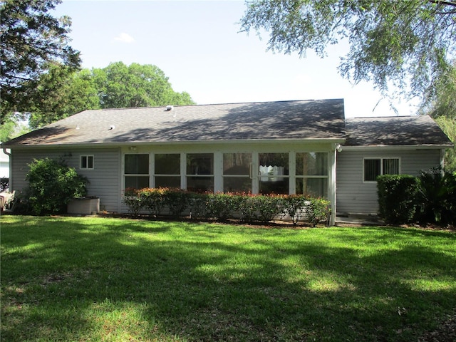 back of property featuring a lawn and a shingled roof