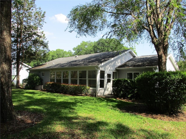 back of property with a yard and roof with shingles