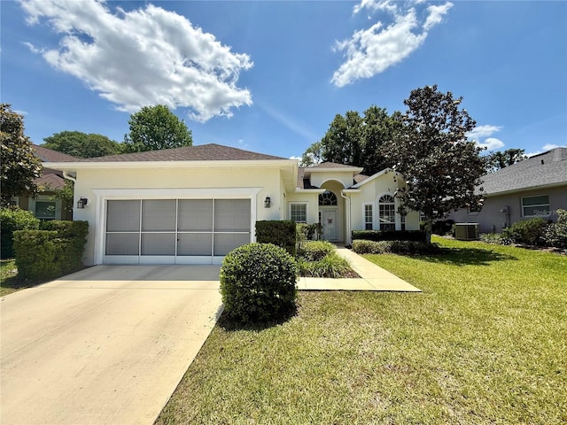 ranch-style home featuring an attached garage, stucco siding, a front yard, central AC unit, and driveway