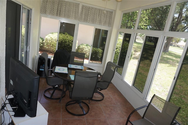 sunroom with outdoor dining area, tile patterned floors, and ceiling fan