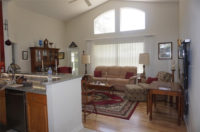 living room featuring light wood-type flooring, a ceiling fan, and high vaulted ceiling