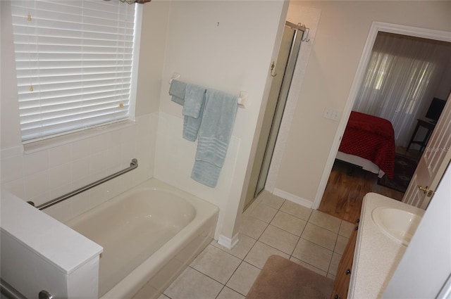 bathroom featuring ensuite bath, tile patterned floors, baseboards, a shower stall, and a bath