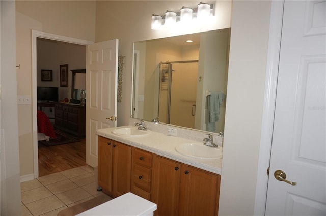 bathroom featuring tile patterned flooring, a sink, a stall shower, and double vanity