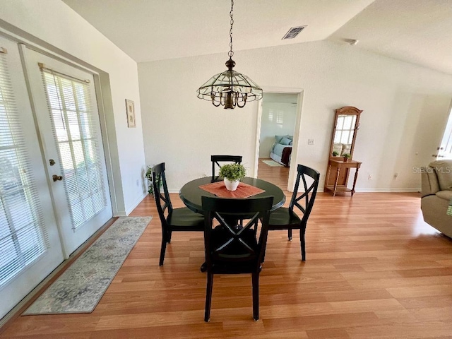 dining room featuring a chandelier, vaulted ceiling, light wood-style flooring, and baseboards