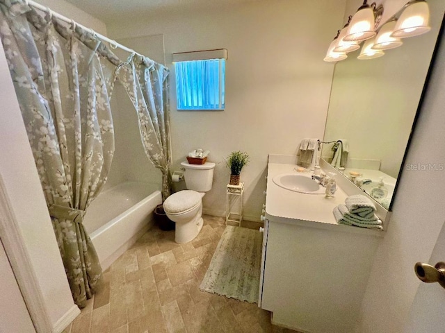 bathroom with toilet, vanity, shower / tub combo, stone finish floors, and baseboards
