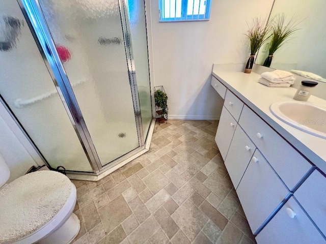 bathroom featuring baseboards, a stall shower, vanity, and stone finish floors
