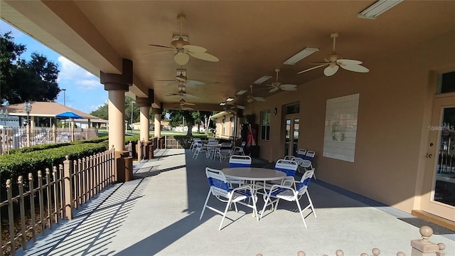 view of patio with fence, a ceiling fan, and outdoor dining space