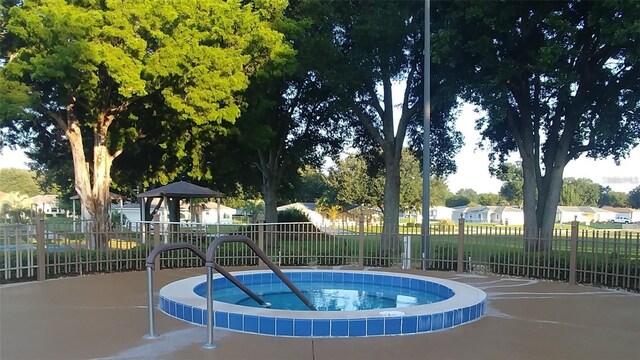 view of swimming pool featuring fence and a community hot tub