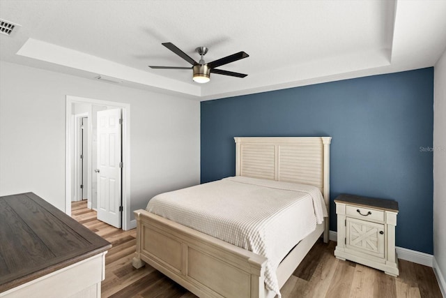 9 Walnut Run, Ocala, FL 34480 - bedroom featuring a tray ceiling, baseboards, visible vents, and wood finished floors