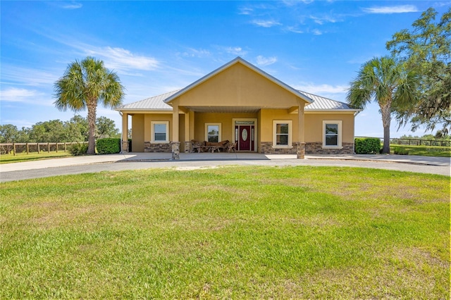 view of front of house featuring stone siding, stucco siding, a front yard, a standing seam roof, and metal roof