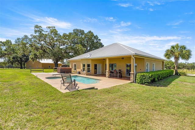 back of house featuring stucco siding, a patio area, metal roof, a lawn, and a hot tub