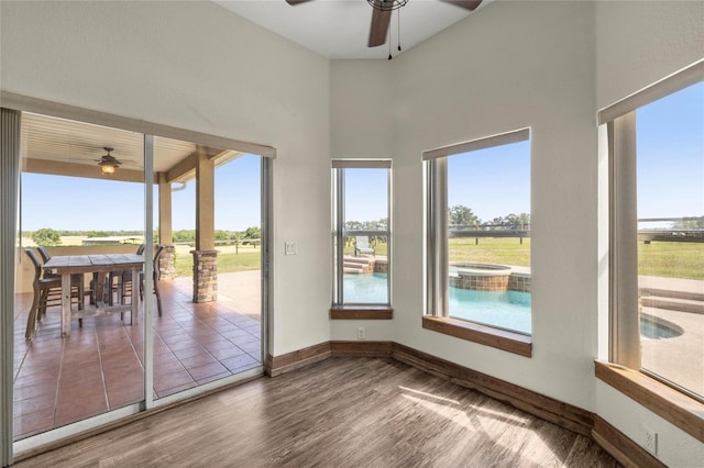 unfurnished sunroom with plenty of natural light, baseboards, a jacuzzi, and wood finished floors