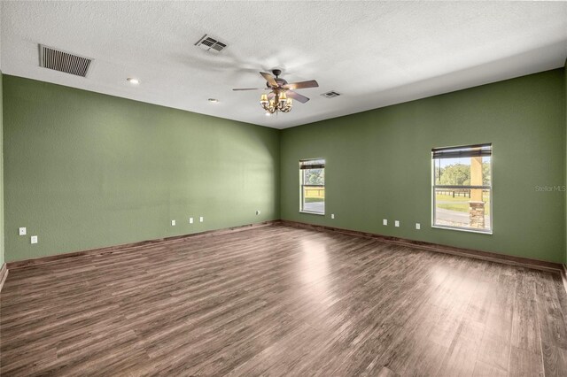 empty room featuring a ceiling fan, visible vents, and wood finished floors