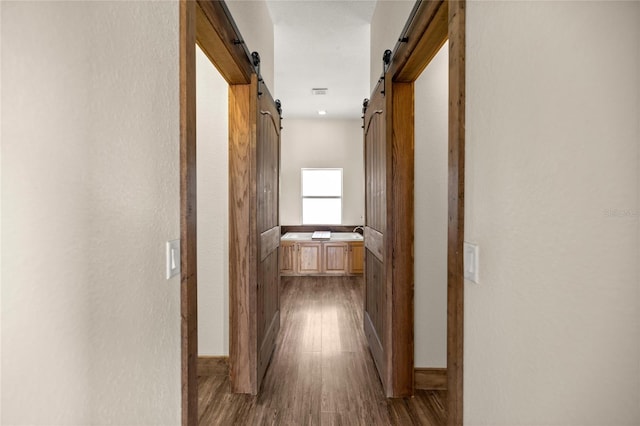 hall featuring a barn door and dark wood-style floors