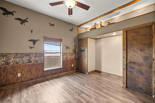 interior space featuring wainscoting, wood finished floors, and lofted ceiling