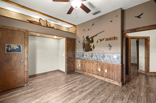 unfurnished bedroom featuring wainscoting, wood finished floors, and visible vents