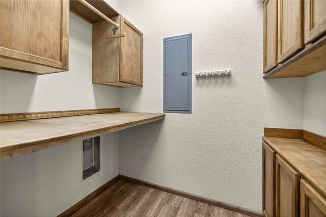 washroom with baseboards, electric panel, dark wood finished floors, and cabinet space