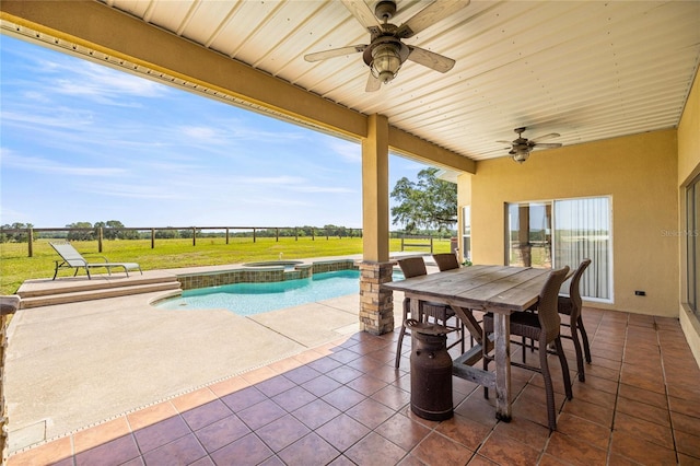 view of patio featuring fence, outdoor dining space, ceiling fan, and a pool with connected hot tub