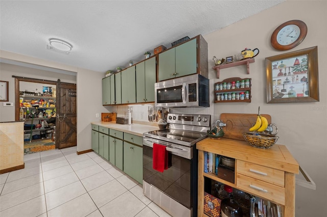4710 SE 30th Ct, Ocala, FL 34480 - kitchen with light countertops, a textured ceiling, stainless steel appliances, light tile patterned floors, and green cabinets