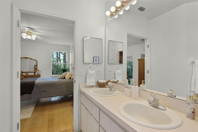 bathroom with ensuite bath, wood finished floors, ceiling fan, and double vanity