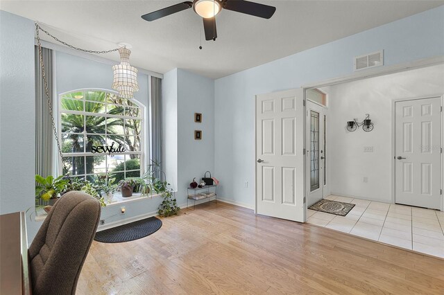 foyer entrance featuring ceiling fan, light wood finished floors, and a chandelier