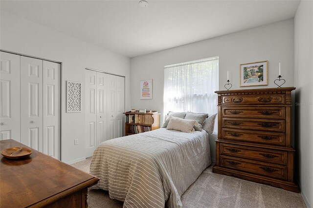carpeted bedroom featuring multiple closets and baseboards