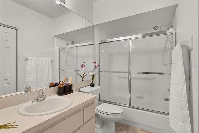 bathroom with enclosed tub / shower combo, vanity, and toilet