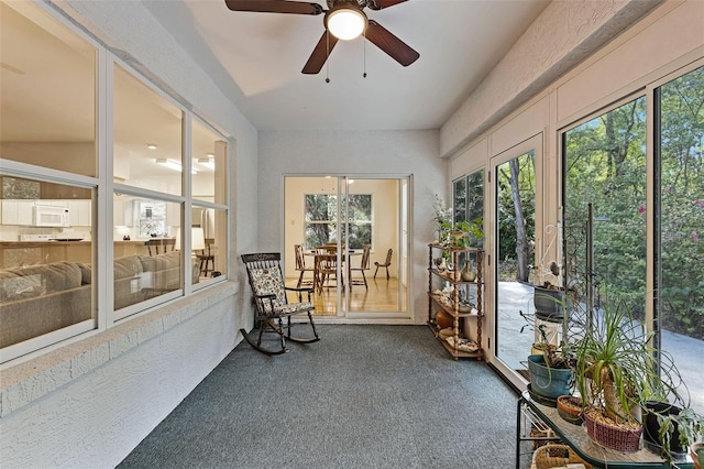sunroom featuring a textured wall, carpet floors, and plenty of natural light