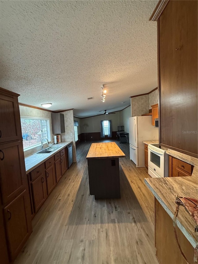 kitchen featuring a sink, a textured ceiling, butcher block counters, and white appliances