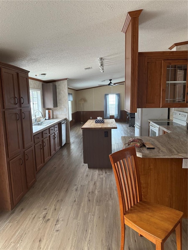 kitchen with electric range, a textured ceiling, wood finished floors, and dishwasher
