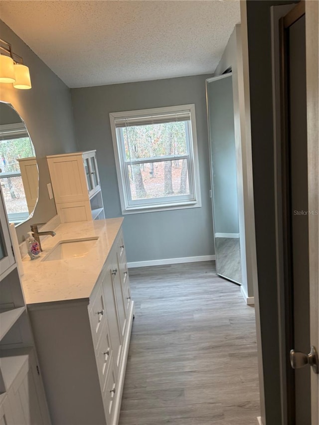 bathroom with vanity, baseboards, a textured ceiling, and wood finished floors