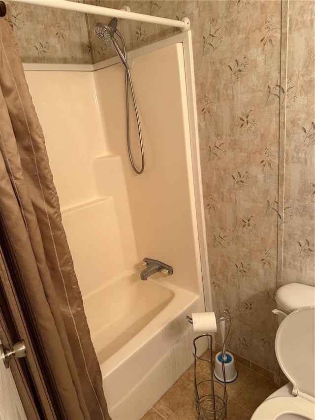 bathroom featuring tile patterned floors, wallpapered walls, toilet, and shower / tub combo