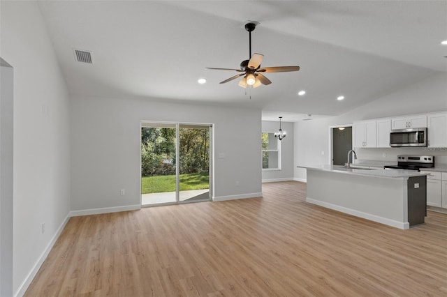 kitchen with open floor plan, appliances with stainless steel finishes, a sink, and light wood-style floors