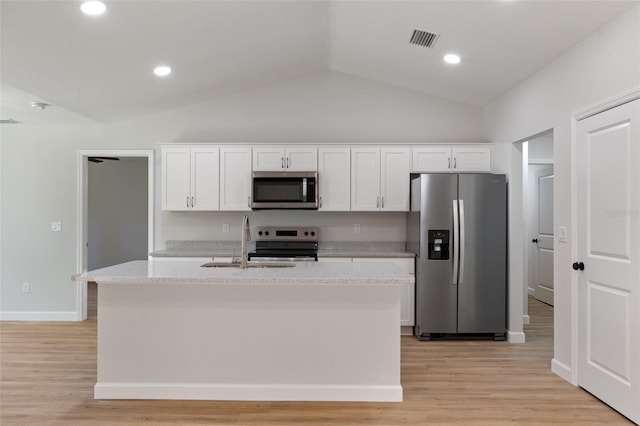 kitchen featuring visible vents, white cabinets, a sink, vaulted ceiling, and stainless steel appliances