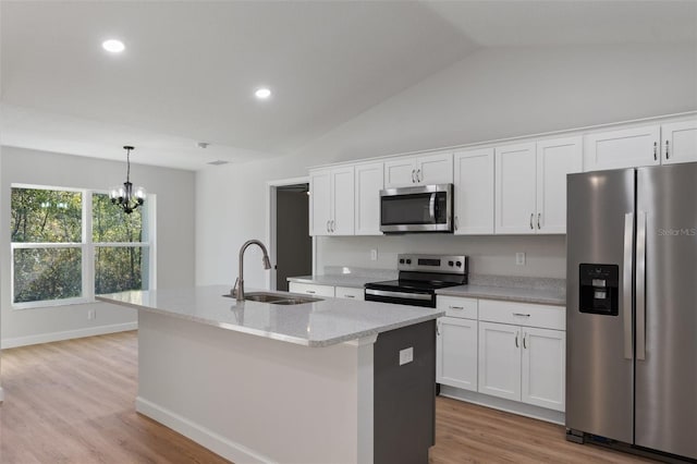kitchen with a center island with sink, a sink, light wood finished floors, appliances with stainless steel finishes, and a notable chandelier