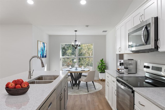 kitchen featuring an inviting chandelier, appliances with stainless steel finishes, a sink, light wood-type flooring, and visible vents