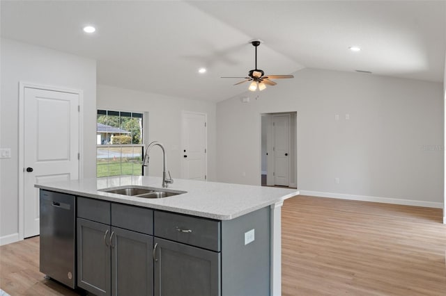 kitchen featuring a sink, light wood-type flooring, stainless steel dishwasher, gray cabinetry, and a center island with sink