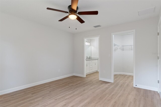 unfurnished bedroom with light wood finished floors, baseboards, a spacious closet, visible vents, and a closet