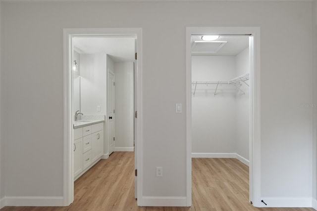 unfurnished bedroom with baseboards, a closet, light wood finished floors, and a spacious closet