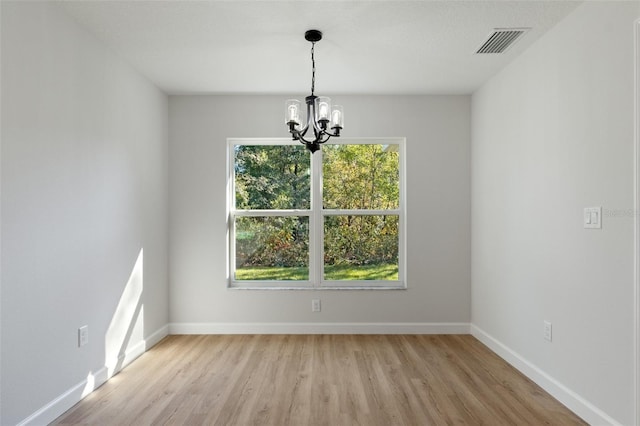 unfurnished dining area with visible vents, light wood-style floors, baseboards, and a notable chandelier