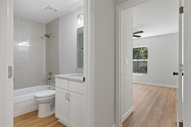 bathroom with visible vents, shower / tub combination, wood finished floors, vanity, and toilet
