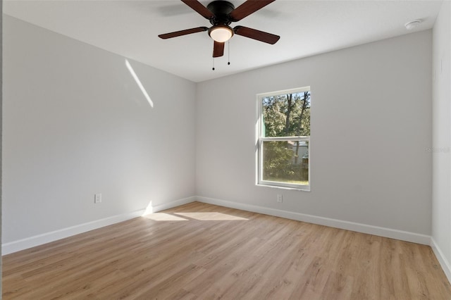 unfurnished room with light wood-type flooring, a ceiling fan, and baseboards