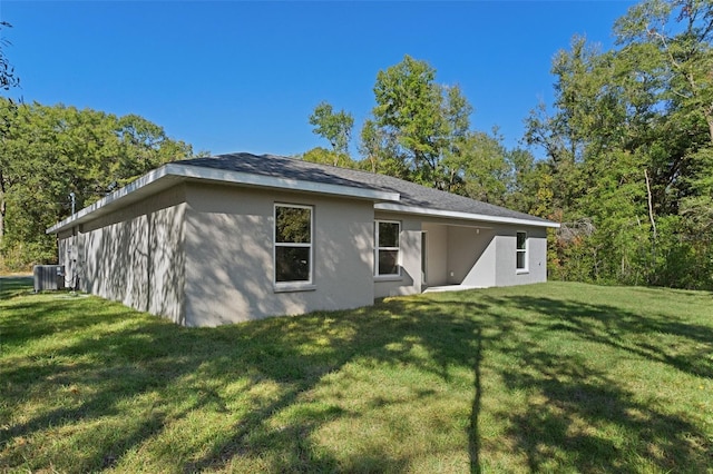 rear view of house featuring stucco siding, a yard, and cooling unit