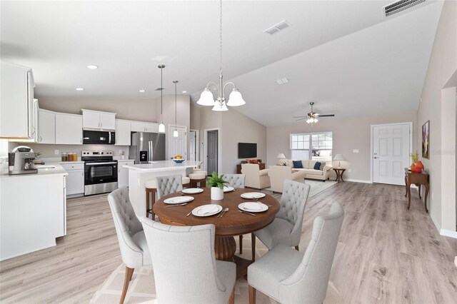 dining area with vaulted ceiling, light wood-style floors, ceiling fan, baseboards, and a chandelier