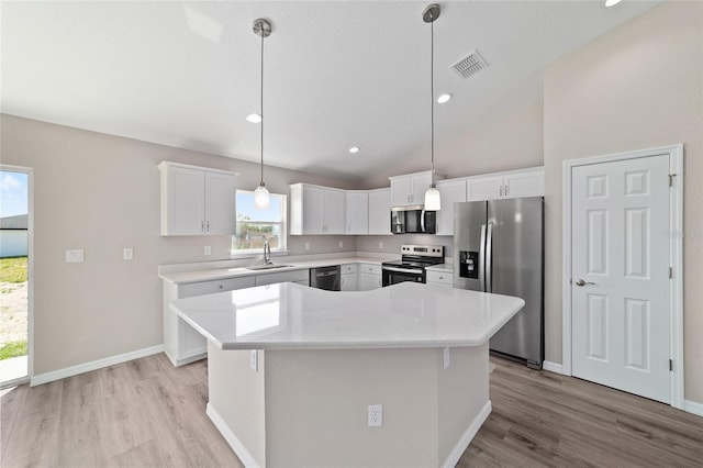 kitchen with appliances with stainless steel finishes, a sink, light wood finished floors, plenty of natural light, and lofted ceiling